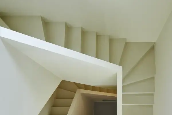 Escalera moderna de diseño minimalista con revestimiento blanco y peldaños de madera clara.