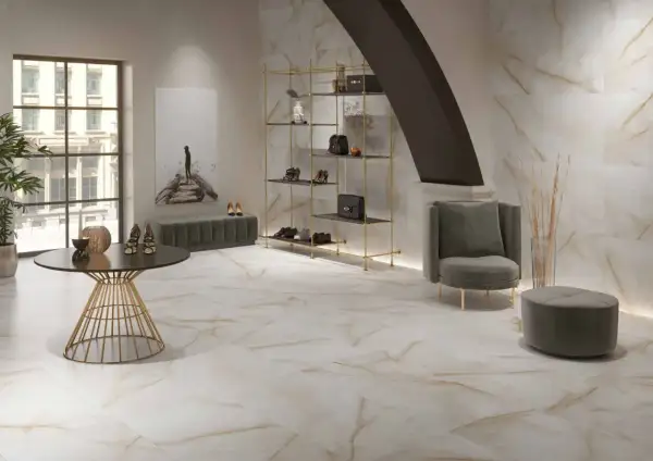 Elegantes suelos pintados con pintura imitan mármol veteado, complementando un salón moderno con estanterías doradas y mobiliario de terciopelo.